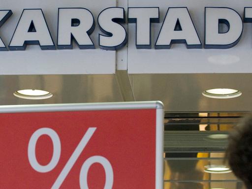 Eine Passantin geht am Dienstag (08.06.vor dem Karstadt-Warenhaus in Münster an einem Plakat mit dem Aufdruck "Reduziert" vorbei.