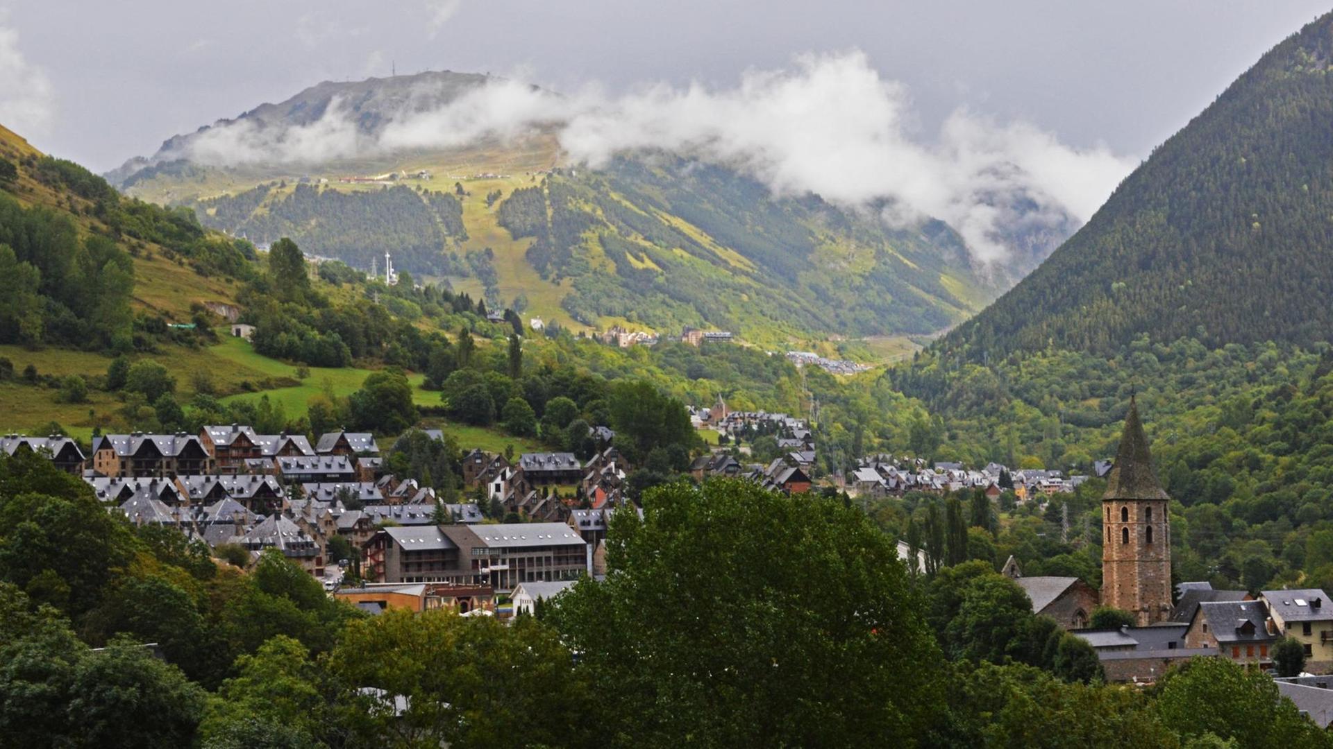 Blick auf das Arantal. Im Vordergrund ein Dorf mit Wohnhäusern und Kirche, im Hintergrund die Pyrenäen. Blick auf das Arantal. Im Vordergrund ein Dorf mit Wohnhäusern und Kirche, im Hintergrund die Pyrenäen.