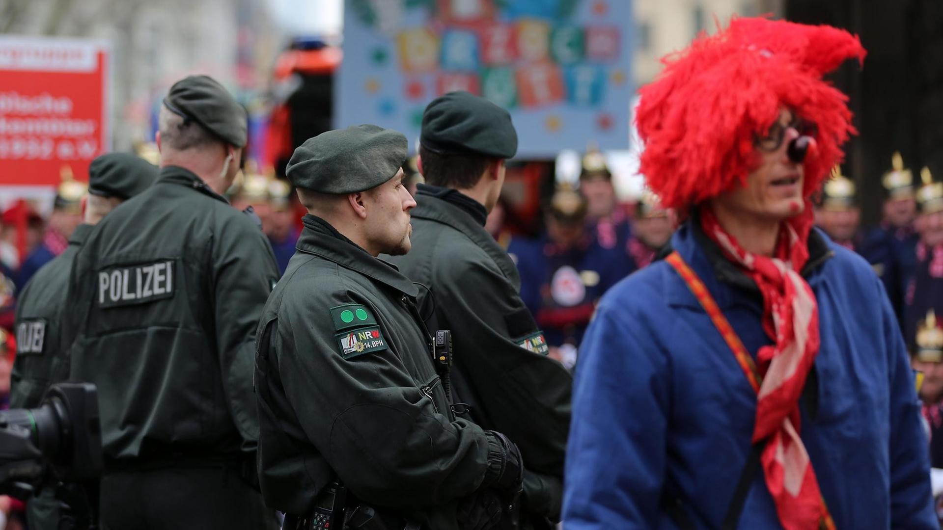 Polizisten stehen am 16.02.2015 in Köln (Nordrhein-Westfalen) neben Karnevalisten am Zugweg. Polizisten stehen am 16.02.2015 in Köln (Nordrhein-Westfalen) neben Karnevalisten am Zugweg.