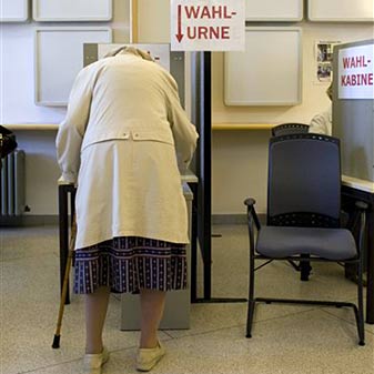Eine ältere Frau wirft im Wahlamt in Bremen Ihren Stimmzettel in eine Wahlurne.