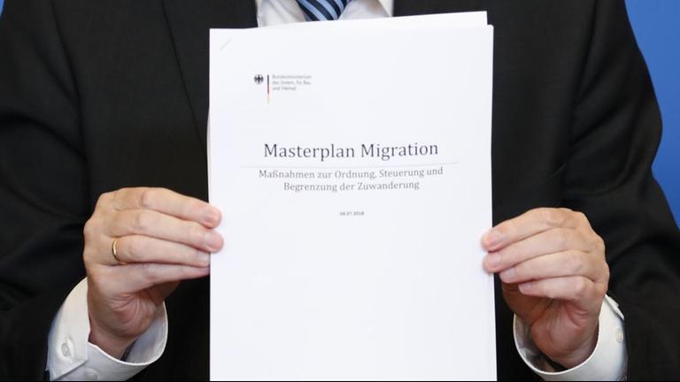 Seehofer hält ein Exemplar des "Masterplan Migration" in die Kamera. Seehofer hält ein Exemplar des "Masterplan Migration" in die Kamera.