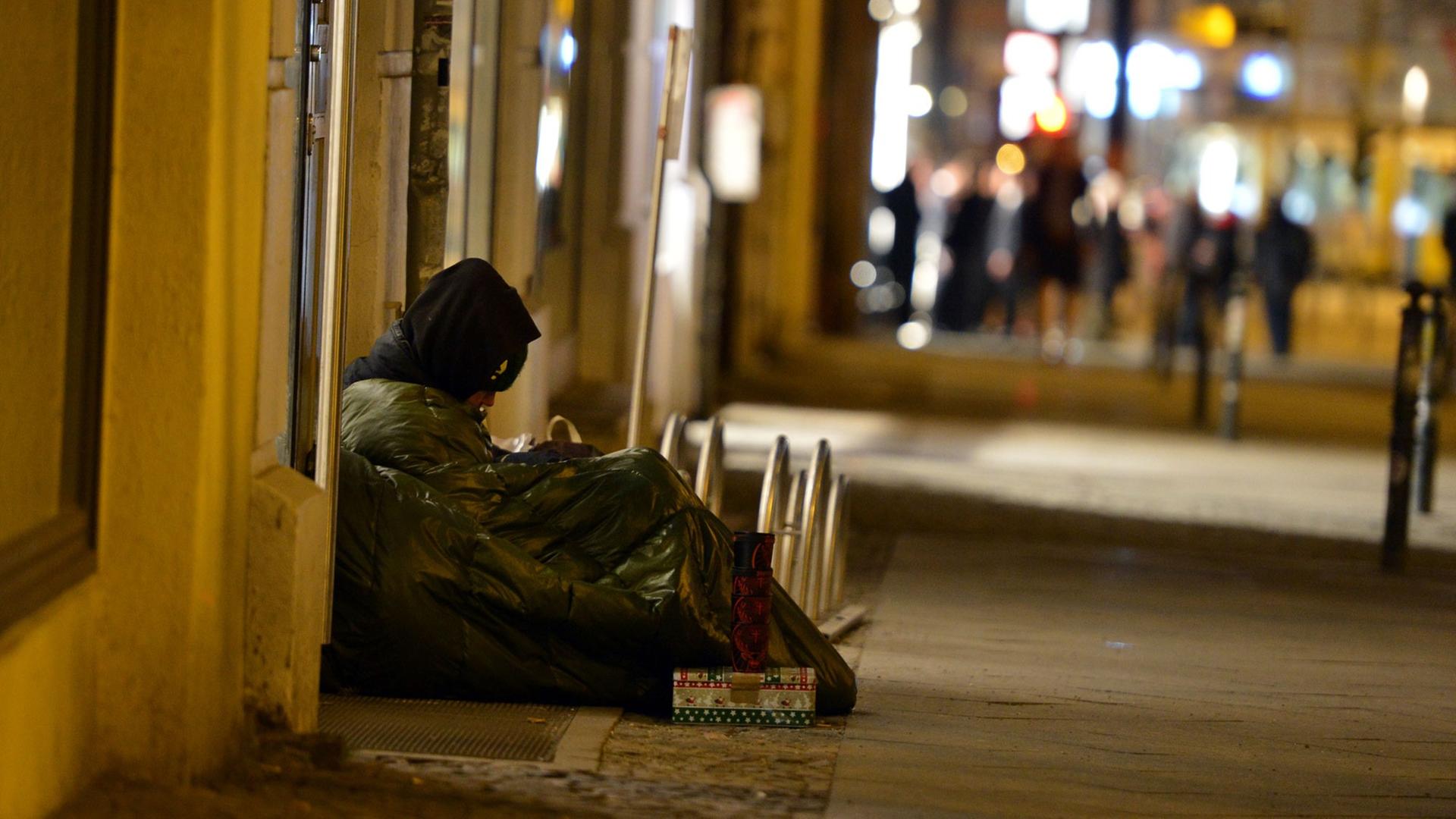 Ein Obdachloser sitzt im Februar 2014 in Berlin Mitte auf dem Gehweg.