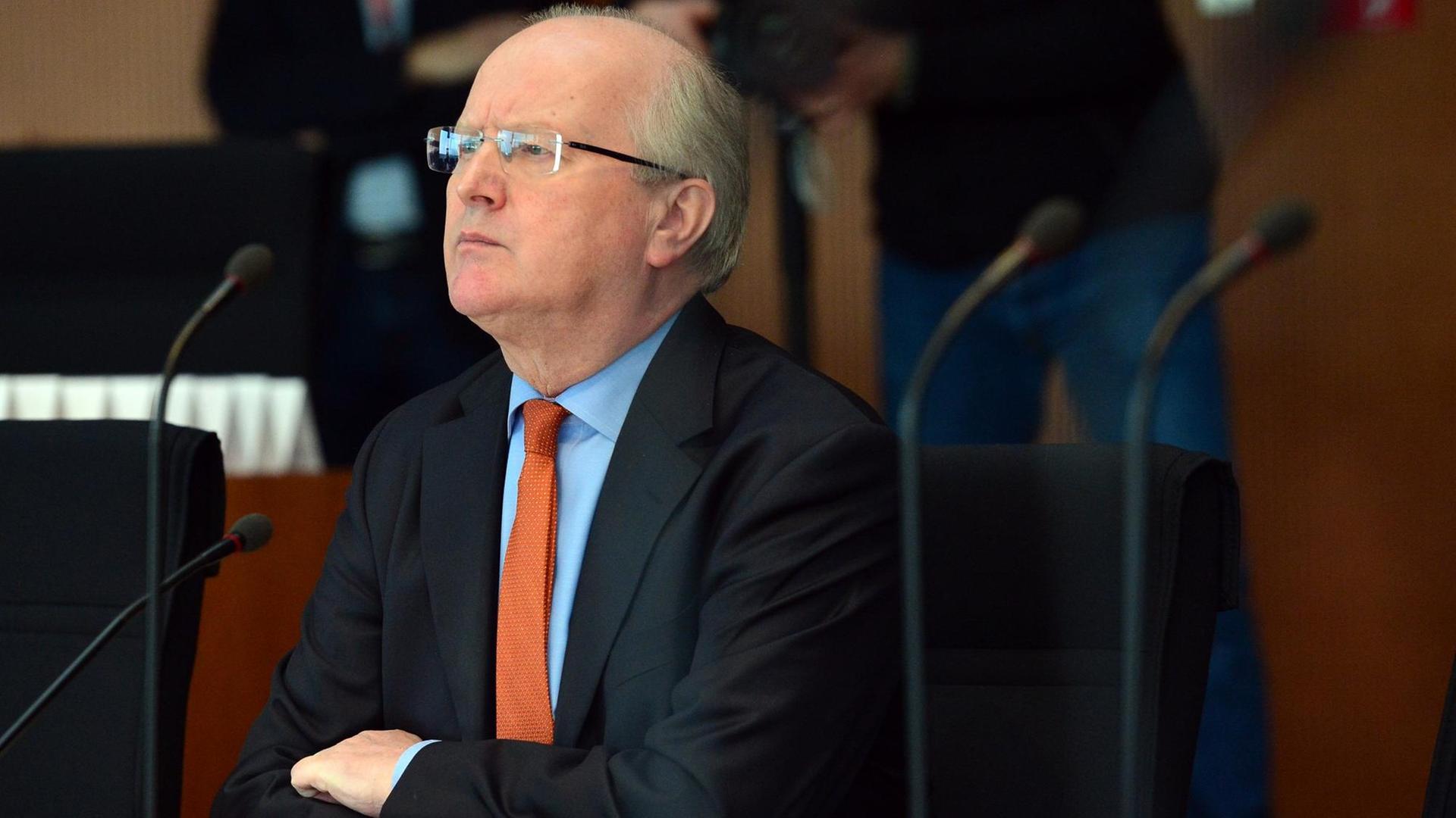 Fritsche sitzt mit verschränkten Armen und ernstem Blick an einem Tisch vor einem Mikrofon. Fritsche sitzt mit verschränkten Armen und ernstem Blick an einem Tisch vor einem Mikrofon.