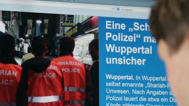 Ein Mann blickt auf einen Computer-Bildschirm, auf dem selbsternannte "Scharia-Polizisten" zu sehen sind.