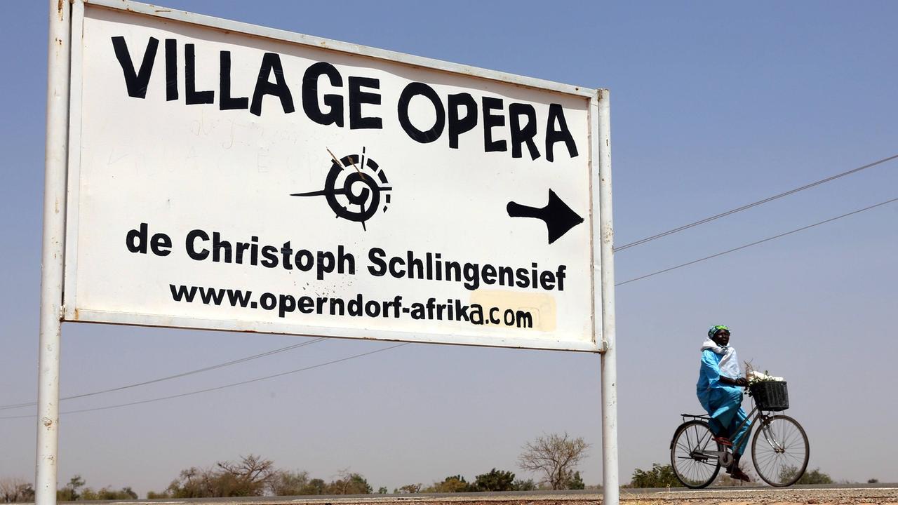 Hinweisschild zu Christoph Schlingensiefs Operndorf in Burkina Faso Hinweisschild zu Christoph Schlingensiefs Operndorf in Burkina Faso
