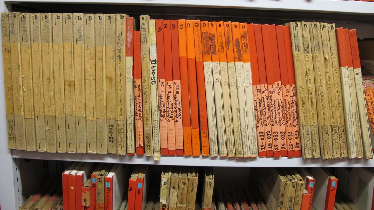 Blick auf drei Regale, in denen schlanke Kartons wie Bücher aufgestellt sind. Blick auf drei Regale, in denen schlanke Kartons wie Bücher aufgestellt sind.