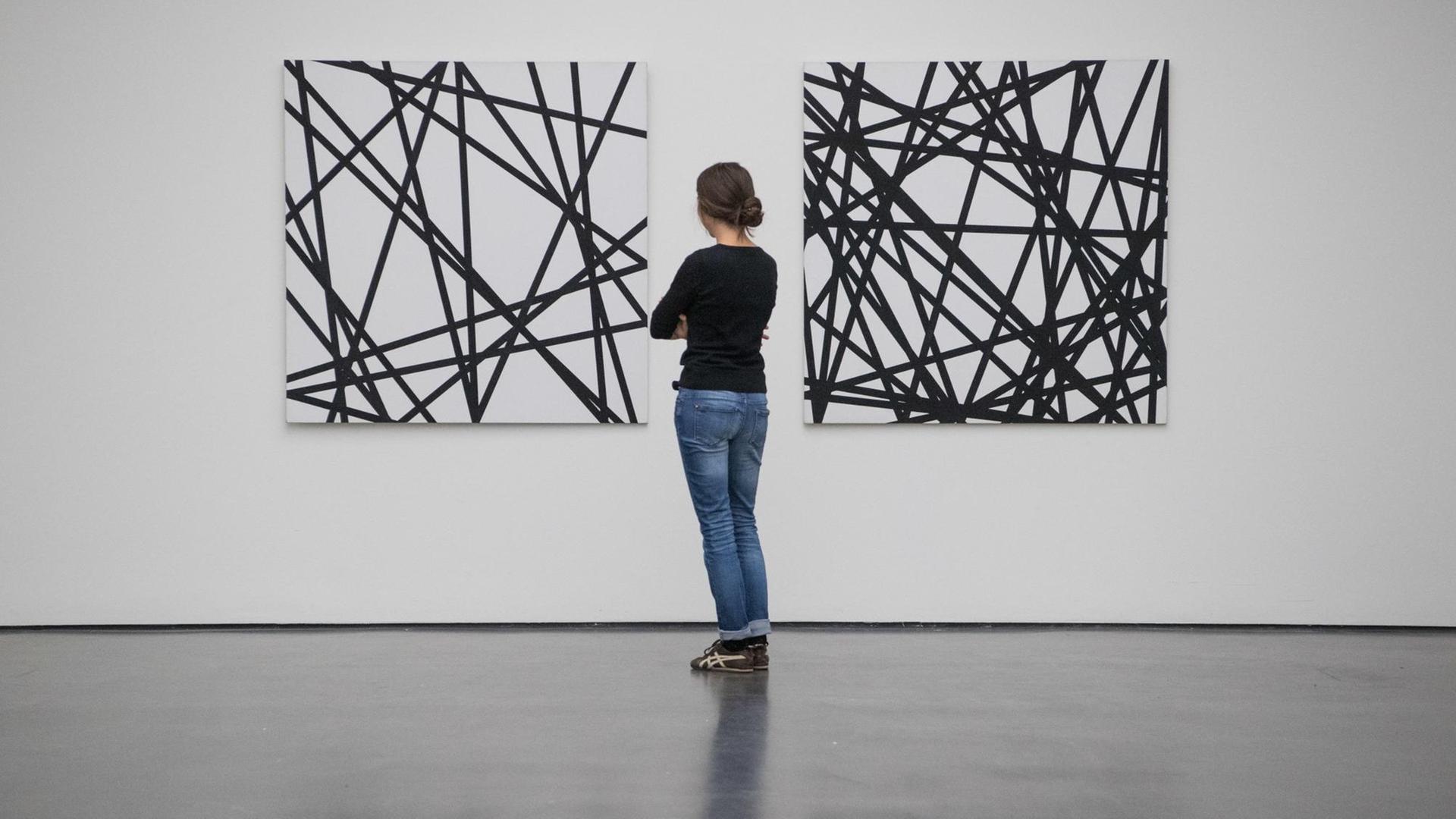 Eine Frau steht im Kunstmuseum in Stuttgart (Baden-Württemberg) in der Ausstellung "un]erwartet" vor den Kunstwerken "20 zufällige Linien" und "40 zufällige Linien" (r) aus dem Jahr 1971 von Francois Morellet.