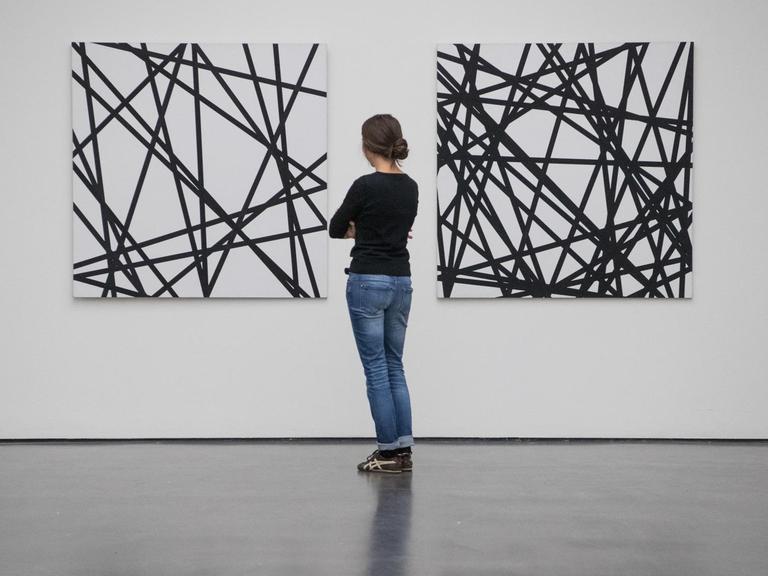 Eine Frau steht im Kunstmuseum in Stuttgart (Baden-Württemberg) in der Ausstellung "un]erwartet" vor den Kunstwerken "20 zufällige Linien" und "40 zufällige Linien" (r) aus dem Jahr 1971 von Francois Morellet.