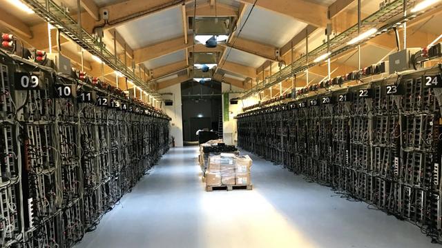 Rechner für das "Schürfen" von Bitcoins im Genesis-Datenzentrum in Keflavik. Ein etwa 100 meter langer Gang - links und rechts stehen schwarze Computer.