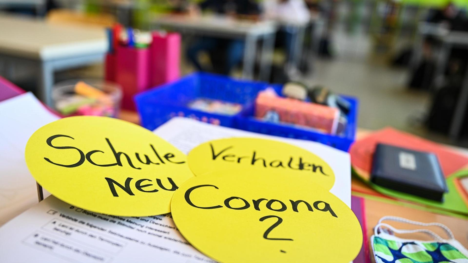 Auf dem Lehrerpult in einem Klassenzimmer liegen drei kreisrunde Papierschilder mit der Aufschrift: "Schule neu", "Verhalten" und "Corona ?", aufgenommen in der Achtalschule in Baienfurt in Baden-Württemberg im Mai 2020 Auf dem Lehrerpult in einem Klassenzimmer liegen drei kreisrunde Papierschilder mit der Aufschrift: "Schule neu", "Verhalten" und "Corona ?", aufgenommen in der Achtalschule in Baienfurt in Baden-Württemberg im Mai 2020