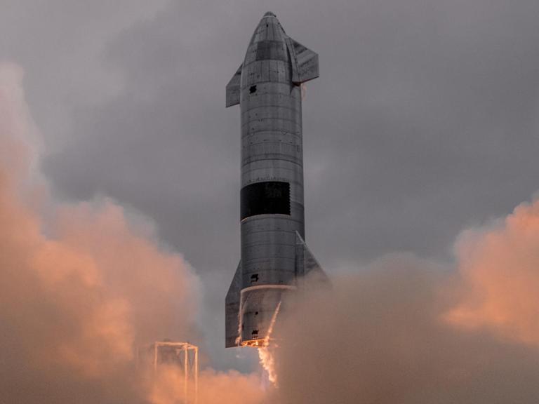 Eine Rakete erhebt sich vor rosaroten Wolken.