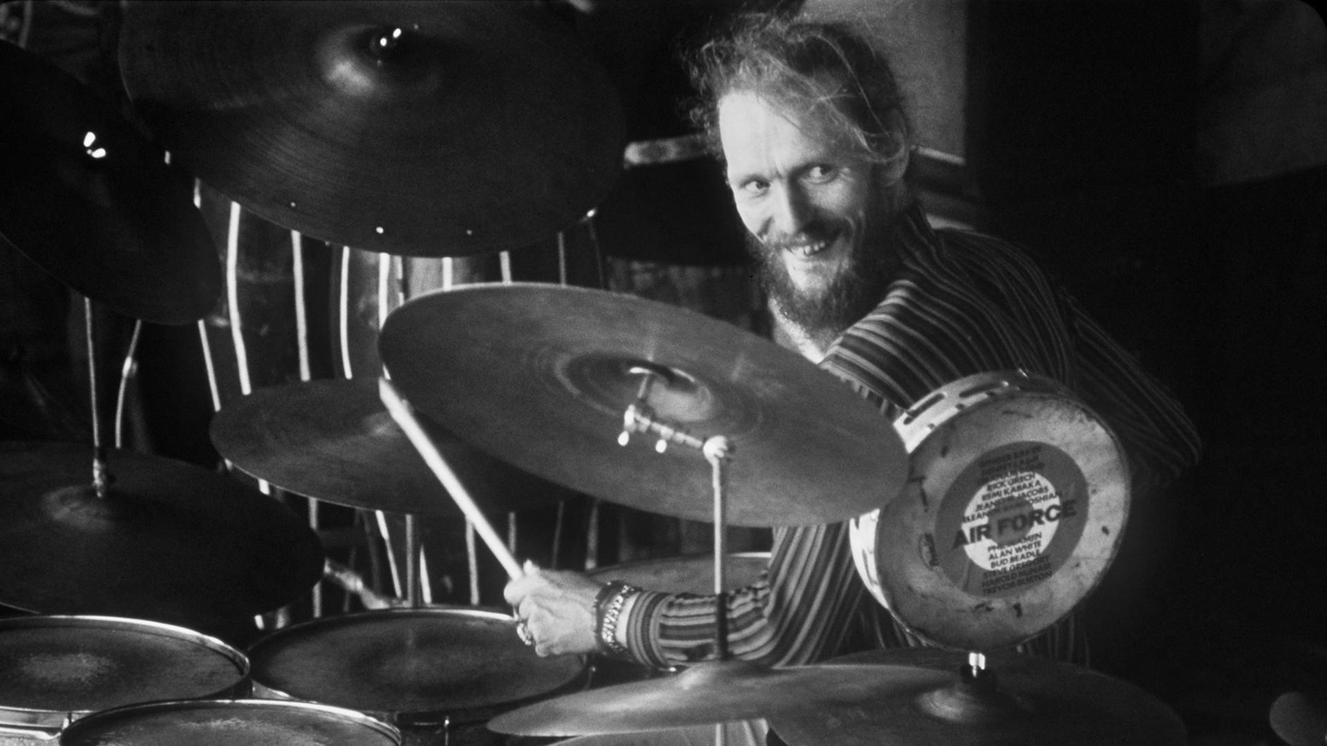 Ginger Baker sitzt am Schlagzeug und grinst. Ginger Baker sitzt am Schlagzeug und grinst.