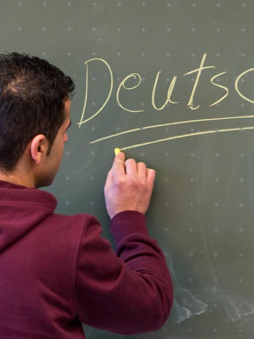 Ein Asylbewerber schreibt in einer Städtischen Berufsschule in Regensburg (Bayern) das Wort "Deutsch" an die Tafel.