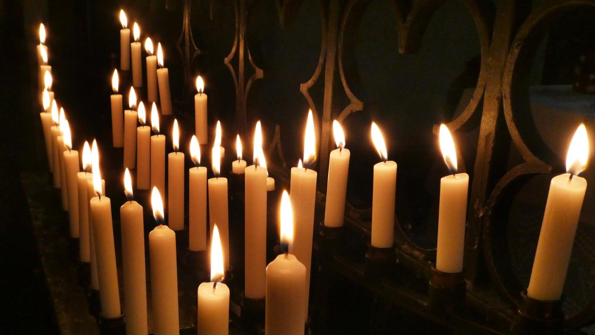 Einige Kerzen brennen in einer dunklen Ecke einer Kirche. Einige Kerzen brennen in einer dunklen Ecke einer Kirche.