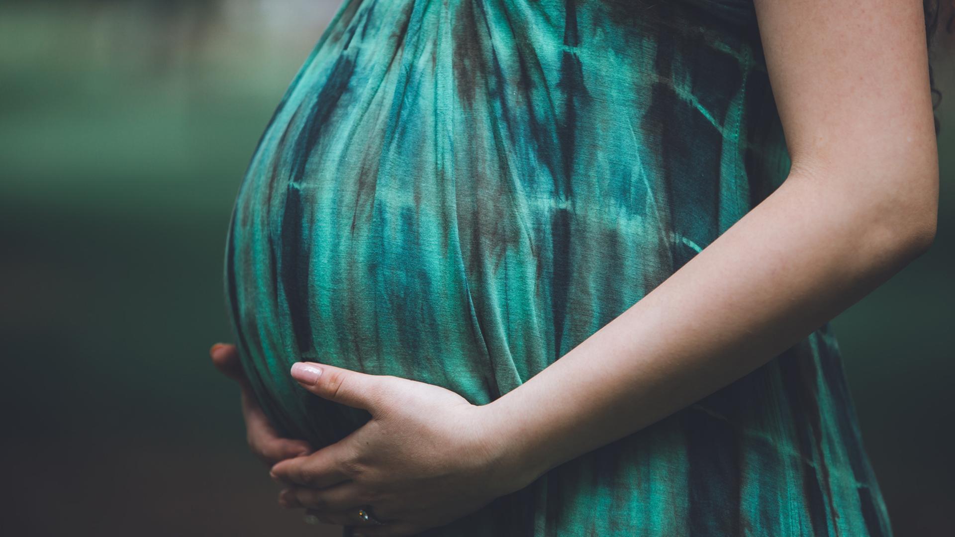 Eine schwangere Frau hält ihren Babybauch. Ein Feature über Geburten, Hebammen und Geburtshäuser.