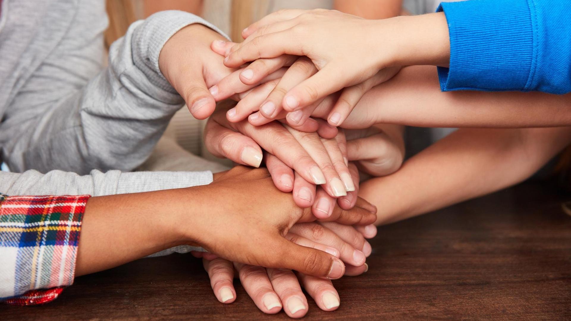 Kinder stapeln ihre Hände auf einem Tisch Kinder stapeln ihre Hände auf einem Tisch