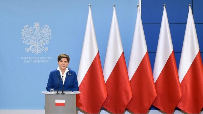 Die neue polnische Ministerpräsidentin Beata Szydlo sitzt an einem prächtigen Schreibtisch, rechts und links von ihr stehen viele polnische Flaggen. Die neue polnische Ministerpräsidentin Beata Szydlo sitzt an einem prächtigen Schreibtisch, rechts und links von ihr stehen viele polnische Flaggen.