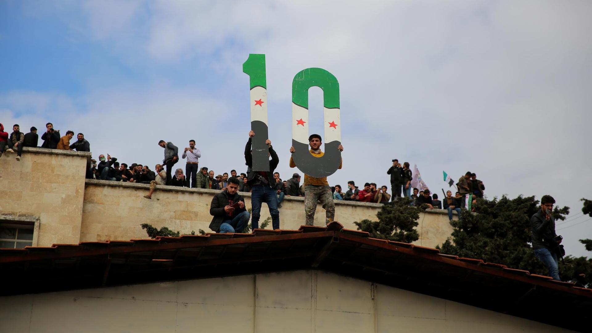 Protestierende in Idlib halten am 15. März 2021 eine 10 in die Höhe zum 10. Jubiläum des Ausbruchs der syrischen Revolution Protestierende in Idlib halten am 15. März 2021 eine 10 in die Höhe zum 10. Jubiläum des Ausbruchs der syrischen Revolution