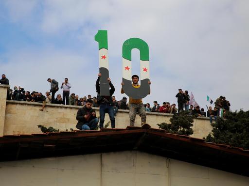 Protestierende in Idlib halten am 15. März 2021 eine 10 in die Höhe zum 10. Jubiläum des Ausbruchs der syrischen Revolution