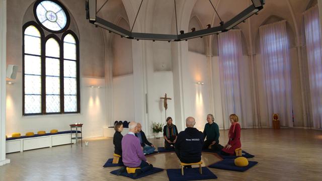 Menschen sitzen in der "Kirche der Stille" im Kreis und meditieren