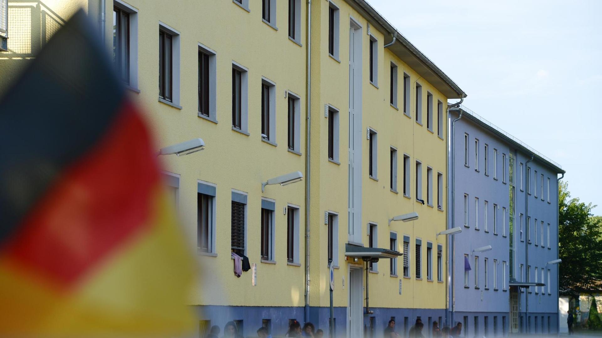Eine Deutschlandfahne weht am 30.06.2014 auf dem Gelände der hessischen Erstaufnahmeeinrichtung für Flüchtlinge Gießen-Meisenbornweg (Hessen) auf einem Autodach. Eine Deutschlandfahne weht am 30.06.2014 auf dem Gelände der hessischen Erstaufnahmeeinrichtung für Flüchtlinge Gießen-Meisenbornweg (Hessen) auf einem Autodach.