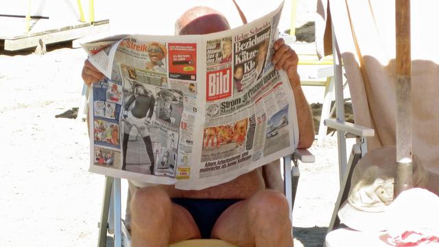 Ein deutscher Urlauber liest die Bild-"Zeitung" am Strand.