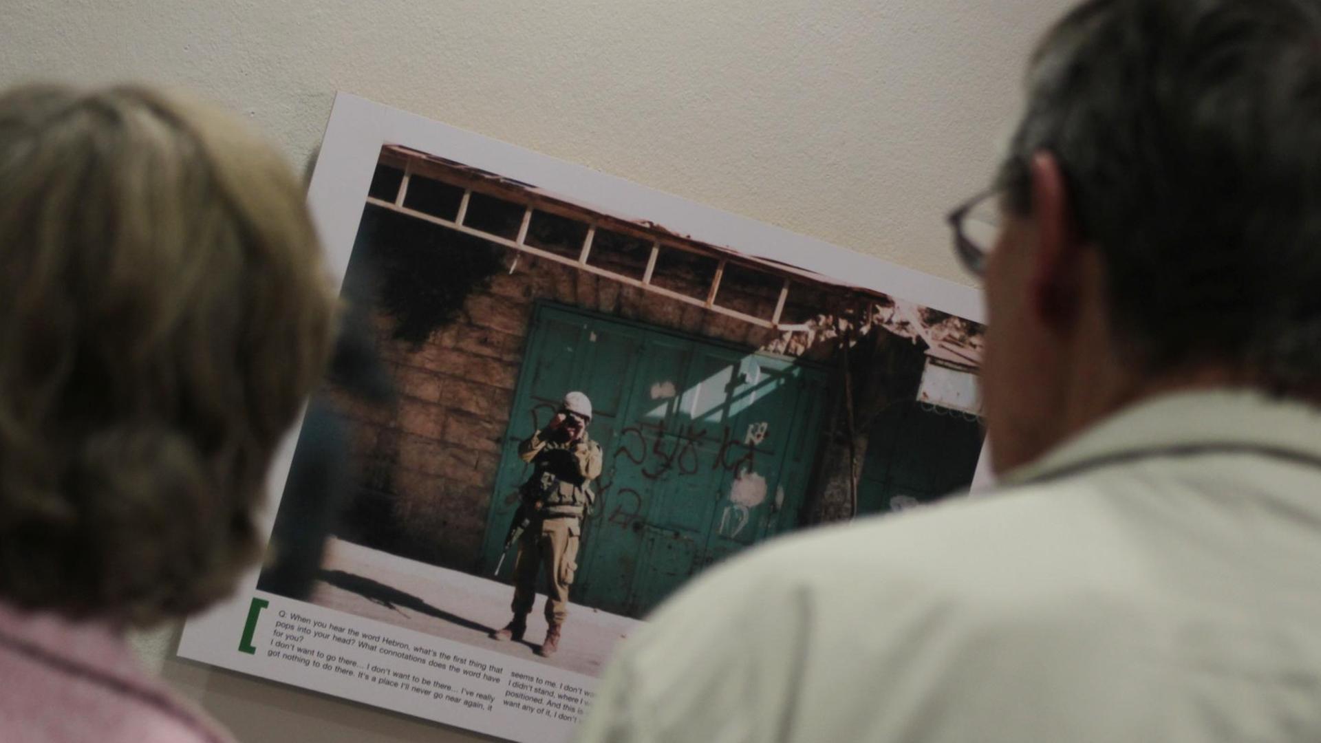 Zwei Besucher betrachten am Donnerstag (13.09.2012) ein Bild der Ausstellung "Breaking the Silence" im Willy-Brandt-Haus in Berlin. Die Ausstellung zeigt Fotos, die israelische Soldaten während ihres Militärdienstes für private Zwecke aufgenommen haben, welche den Besatzungsalltag widerspiegeln.