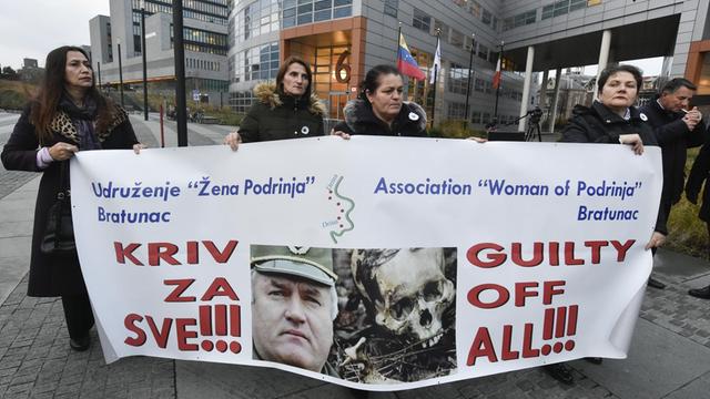 Demonstranten halten vor dem Gebäude des Internationalen Strafgerichtshofs für das ehemalige Jugoslawien in Den Haag ein Plakat mit dem Bild von Ratko Mladic und der Aufschrift "Schuldig in allen Punkten" hoch.