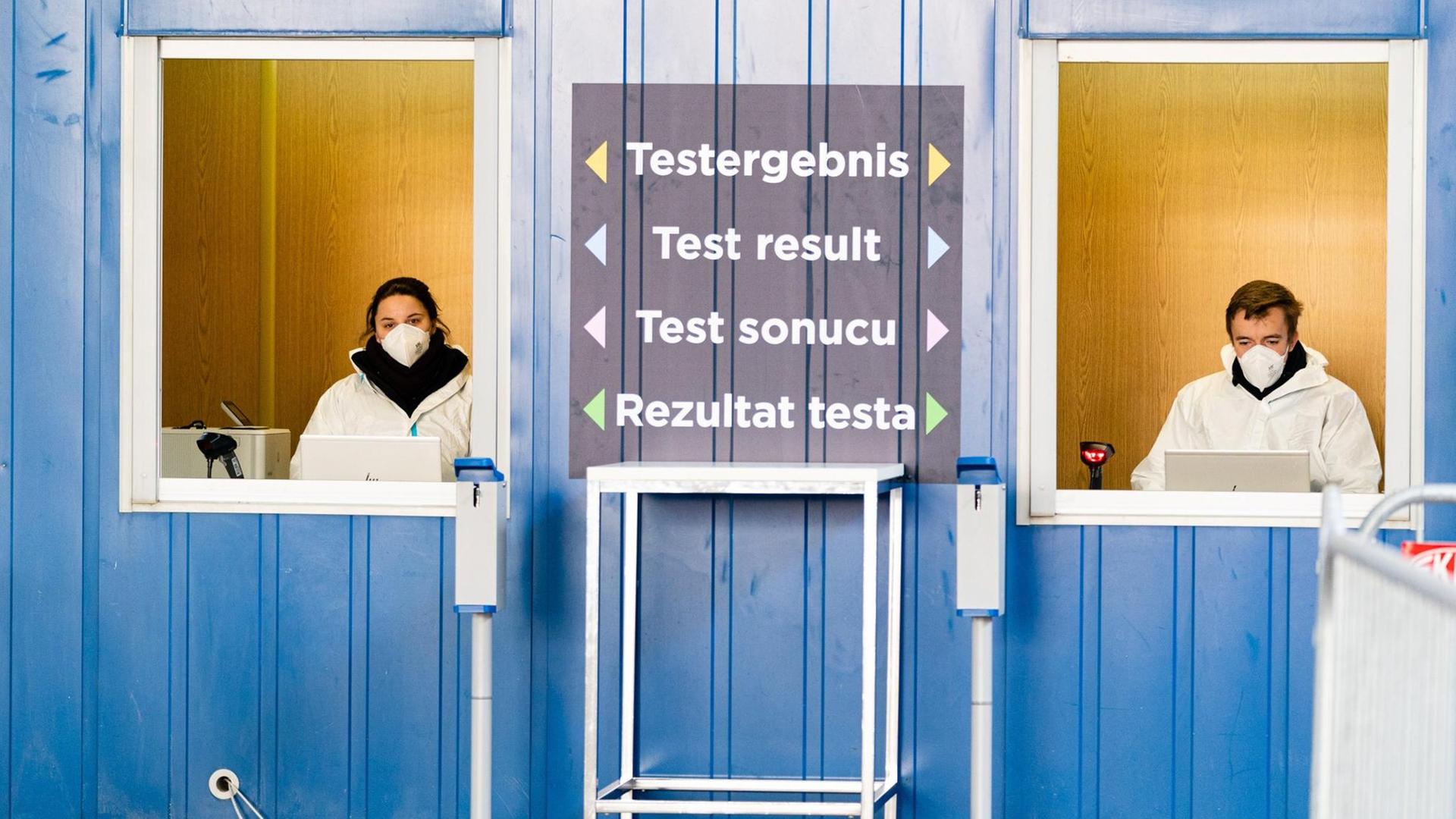 Zwei Personen in Schutzanzügen stehen an der größten Teststrasse Österreichs. Mehrsprachig ist "Testergebnis" zwischen den Fenstern geschrieben. Zwei Personen in Schutzanzügen stehen an der größten Teststrasse Österreichs. Mehrsprachig ist "Testergebnis" zwischen den Fenstern geschrieben.
