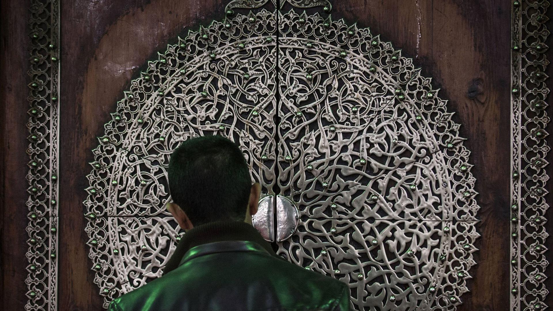 Der Rücken eines Mannes, der vor einer Moschee steht.