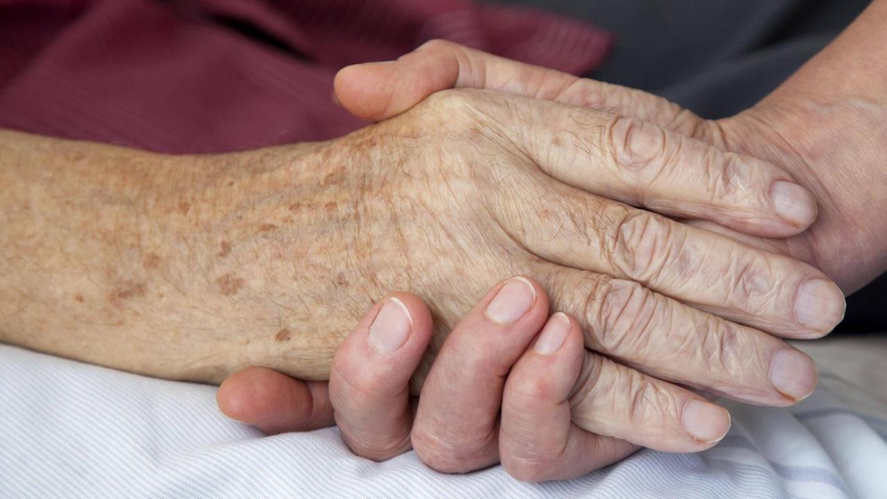 15.07.2010, Nordrhein-Westfalen, Deutschland - Hospiz. Die Hand einer Pflegerin haelt die Hand eines sterbenden Mannes. (QF, ältere, älterer, berühren, Berührung, bettlägerig, europäisch, Fürsorge, fürsorglich, Hände, häusliche Pflege, Menschenwürde, menschenwürdiges Sterben, Nähe, trösten) 00X110715D001.JPG MODEL RELEASE: YES,RELEASE: 15.07.2010, Nordrhein-Westfalen, Deutschland - Hospiz. Die Hand einer Pflegerin haelt die Hand eines sterbenden Mannes. (QF, ältere, älterer, berühren, Berührung, bettlägerig, europäisch, Fürsorge, fürsorglich, Hände, häusliche Pflege, Menschenwürde, menschenwürdiges Sterben, Nähe, trösten) 00X110715D001.JPG MODEL RELEASE: YES,RELEASE: