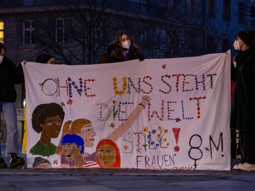 Beim Internationaler Frauentag am 8.März 2021 halten demonstrierende Frauen auf dem Münsterplatz in Bonn ein Banner mit der Aufschrift "Ohne uns steht die Welt still"