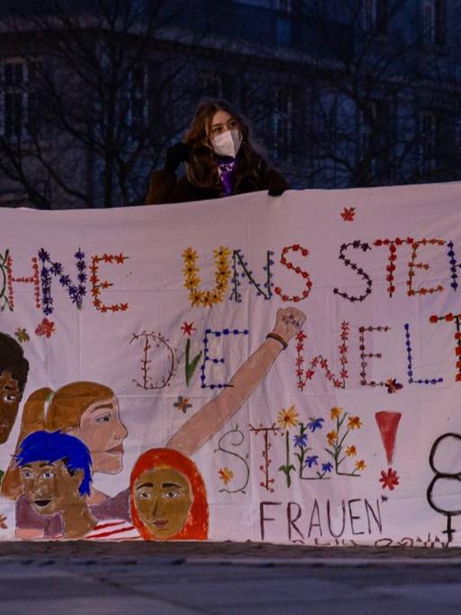 Beim Internationaler Frauentag am 8.März 2021 halten demonstrierende Frauen auf dem Münsterplatz in Bonn ein Banner mit der Aufschrift "Ohne uns steht die Welt still"