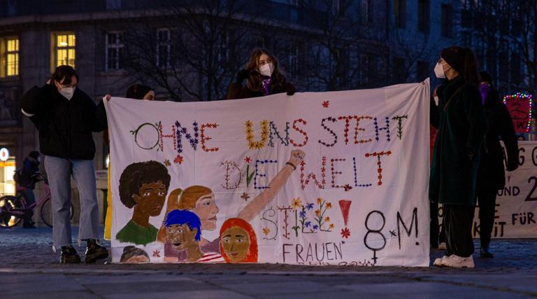 Beim Internationaler Frauentag am 8.März 2021 halten demonstrierende Frauen auf dem Münsterplatz in Bonn ein Banner mit der Aufschrift "Ohne uns steht die Welt still" 