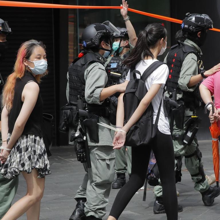 Polizisten in Hongkong führen Demonstranten nach einem Protest mit am Rücken zusammengebundenen Händen ab.