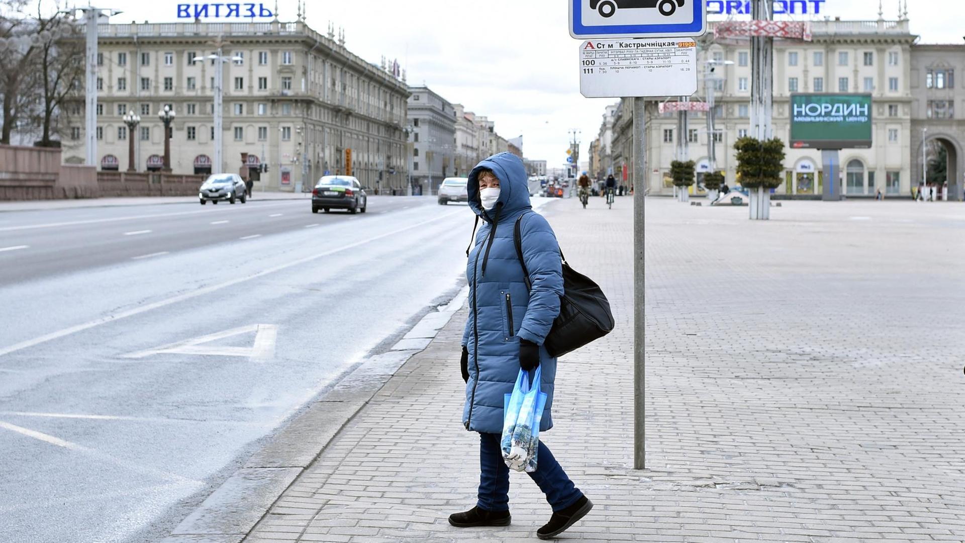 Eine Frau mit Mundschutz an einer Bushaltestelle in Minsk.