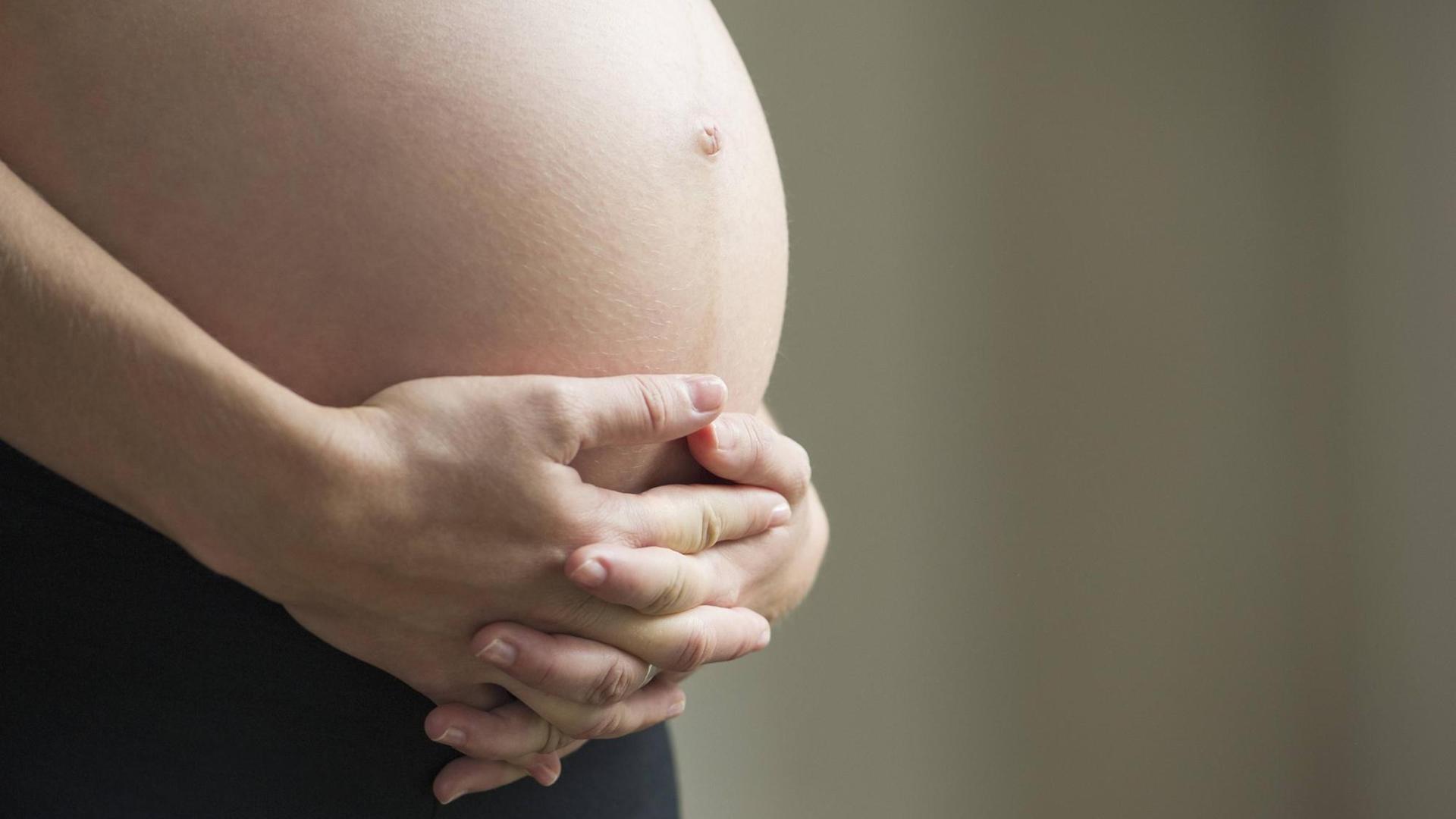 Die Hand einer schwangeren Frau auf ihrem nacktem Bauch. Die Hand einer schwangeren Frau auf ihrem nacktem Bauch.