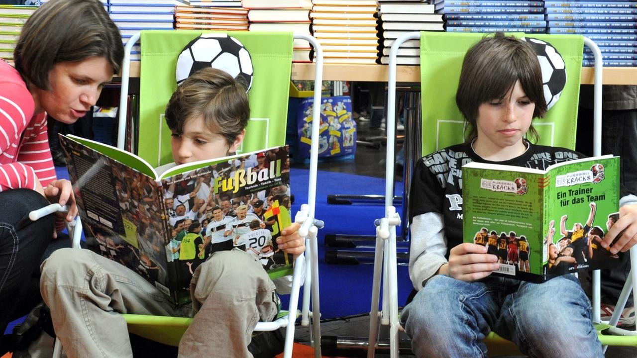 Eine Frau sieht sich auf der Buchmesse in Leipzig mit einem Kind in der Kinderbuchhandlung Fußballbücher an, aufgenommen am 20.03.2010. Eine Frau sieht sich auf der Buchmesse in Leipzig mit einem Kind in der Kinderbuchhandlung Fußballbücher an, aufgenommen am 20.03.2010.
