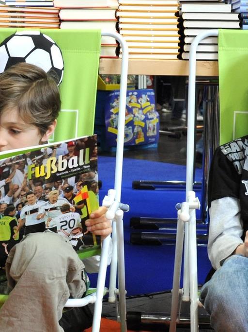Eine Frau sieht sich auf der Buchmesse in Leipzig mit einem Kind in der Kinderbuchhandlung Fußballbücher an, aufgenommen am 20.03.2010.