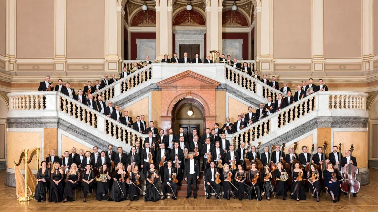 Die Orchestermitglieder stehen auf einer ausladenden, historischen Foyer-Treppe. Die Orchestermitglieder stehen auf einer ausladenden, historischen Foyer-Treppe.
