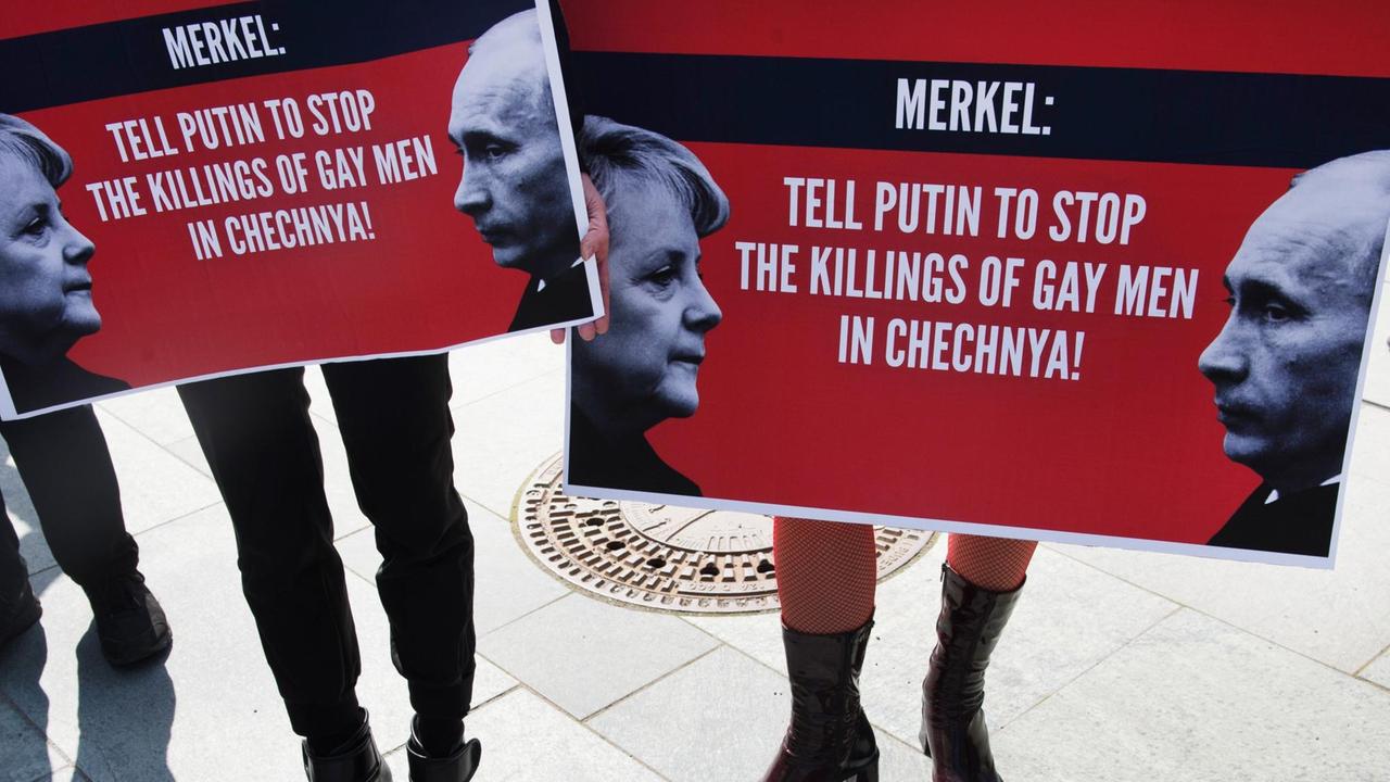 Demonstranten halten am 30.04.2017 in Berlin beim Start einer dreitägigen Mahnwache zum Schutz von Schwulen in Tschetschenien Plakate mit der Aufschrift "Merkel: Tell Putin to Stop the Killings of Gay Men in Chechnya" in den Händen. Demonstranten halten am 30.04.2017 in Berlin beim Start einer dreitägigen Mahnwache zum Schutz von Schwulen in Tschetschenien Plakate mit der Aufschrift "Merkel: Tell Putin to Stop the Killings of Gay Men in Chechnya" in den Händen.