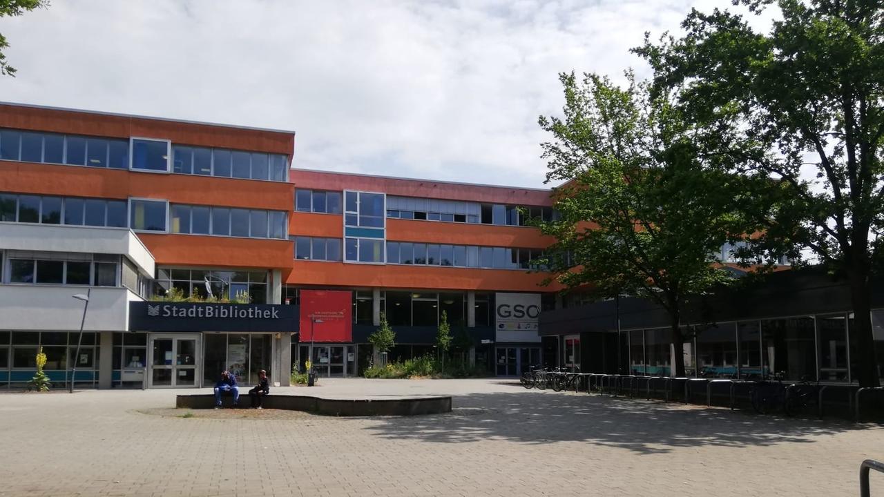 Blick auf ein rotes Schulgebäude mit Schulhof und Bibliothek. Blick auf ein rotes Schulgebäude mit Schulhof und Bibliothek.