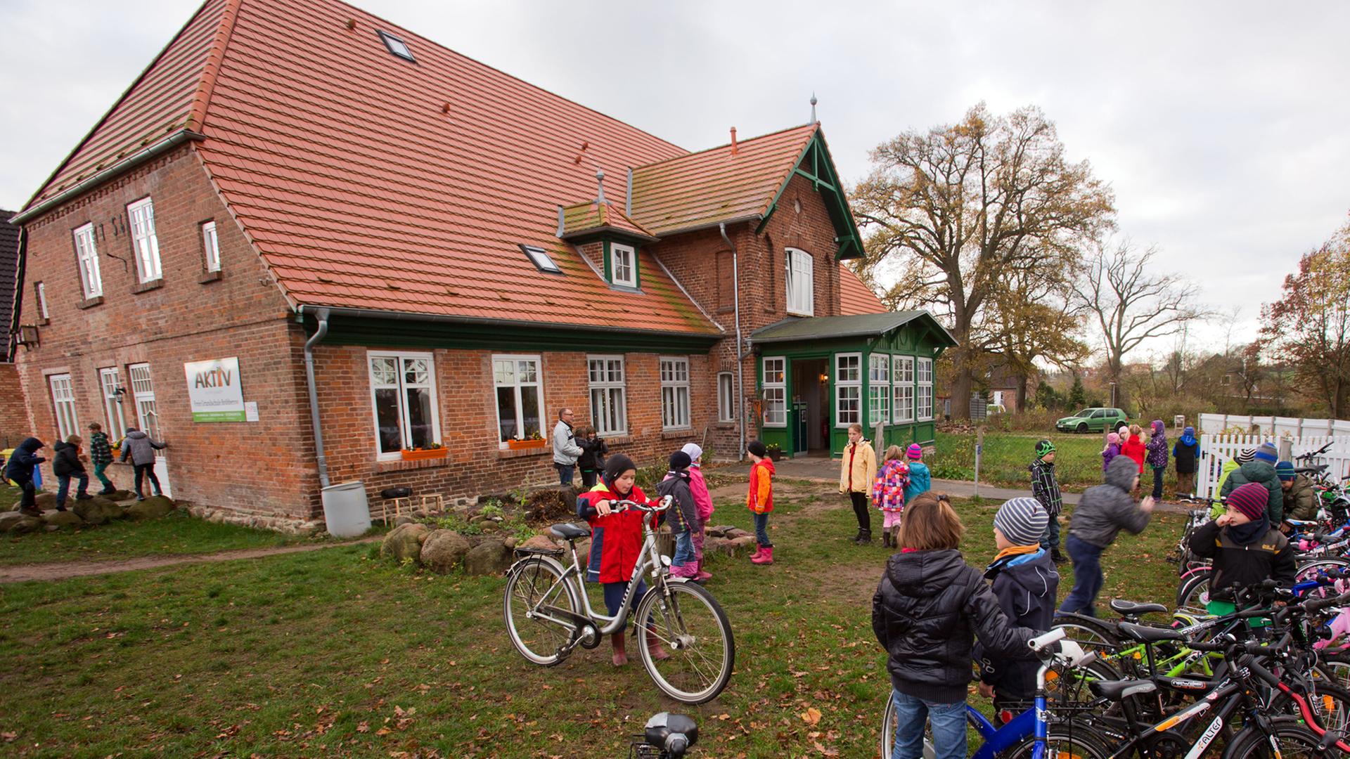 Schüler der privaten Grundschule in Bröbberow stellen auf der Wiese vor dem Schulgebäude ihre Fahrräder ab.
