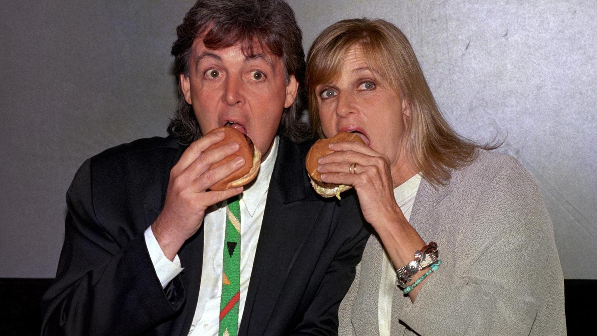 Paul und Linda McCartney posieren für ein Pressefoto und beißen herzhaft in einen vegetarischen Burger. Paul und Linda McCartney posieren für ein Pressefoto und beißen herzhaft in einen vegetarischen Burger.