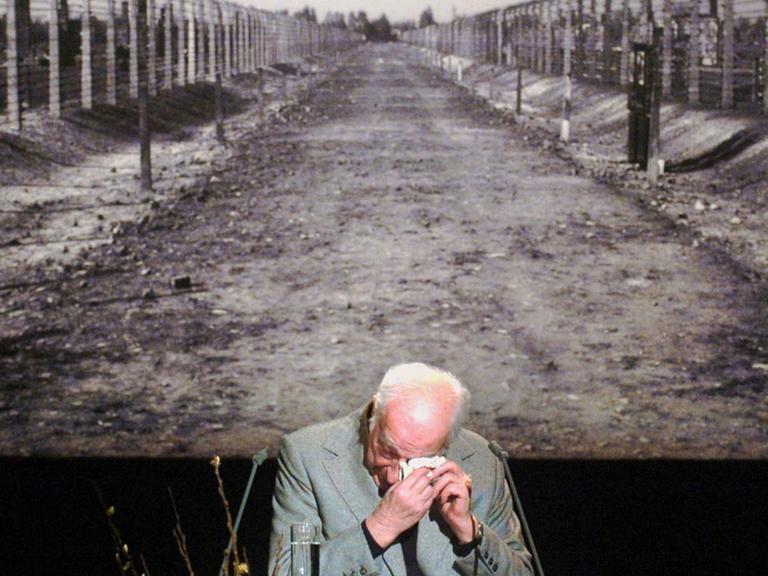 Der Auschwitz-Überlebende Kurt Julius Goldstein wischt sich auf der Gedenkveranstaltung des Internationalen Auschwitz Komitees zur Befreiung des Konzentrationslagers durch die sowjetische Armee mit einem Taschentuch Tränen aus dem Auge. Im Hintergrund ist ein großformatiges Foto des Weges zu sehen, der zu den Krematorien und Gaskammern des Vernichtungslagers führte.