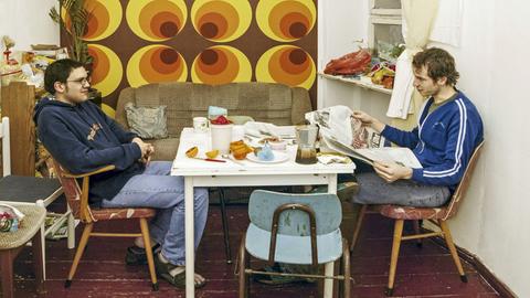 Wohngemeinschaft: Zwei Männer sitzen zuhause in ihrer Küche am Esstisch.