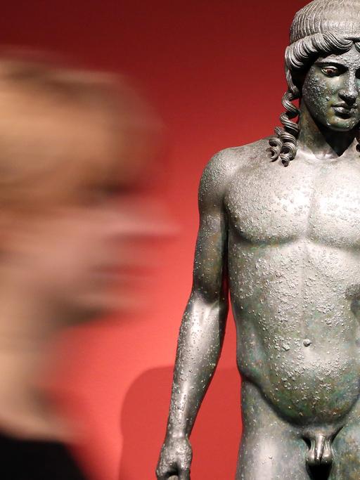 Eine Frau geht in der Ausstellung "Pompeji - Götter, Mythen, Menschen" im Bucerius Kunst Forum in Hamburg an der "Statue des Apollon" entlang.