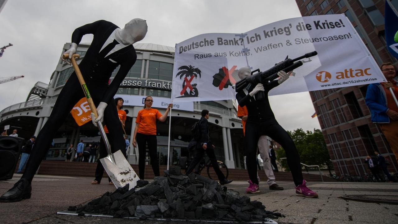 Hessen, Frankfurt am Main: Aktivisten von Attac inszenieren sich bei einer Aktion gegen die Deutsche Bank mit Spaten, Kohle und einem Gewehr.