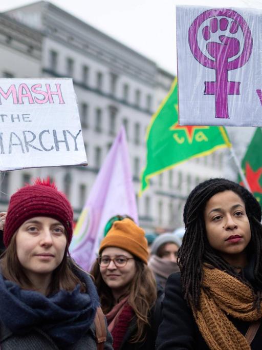 Zwei Frauen halten Plakate, auf denen steht "Smash the Patriarchy" und "Stand up for Women"