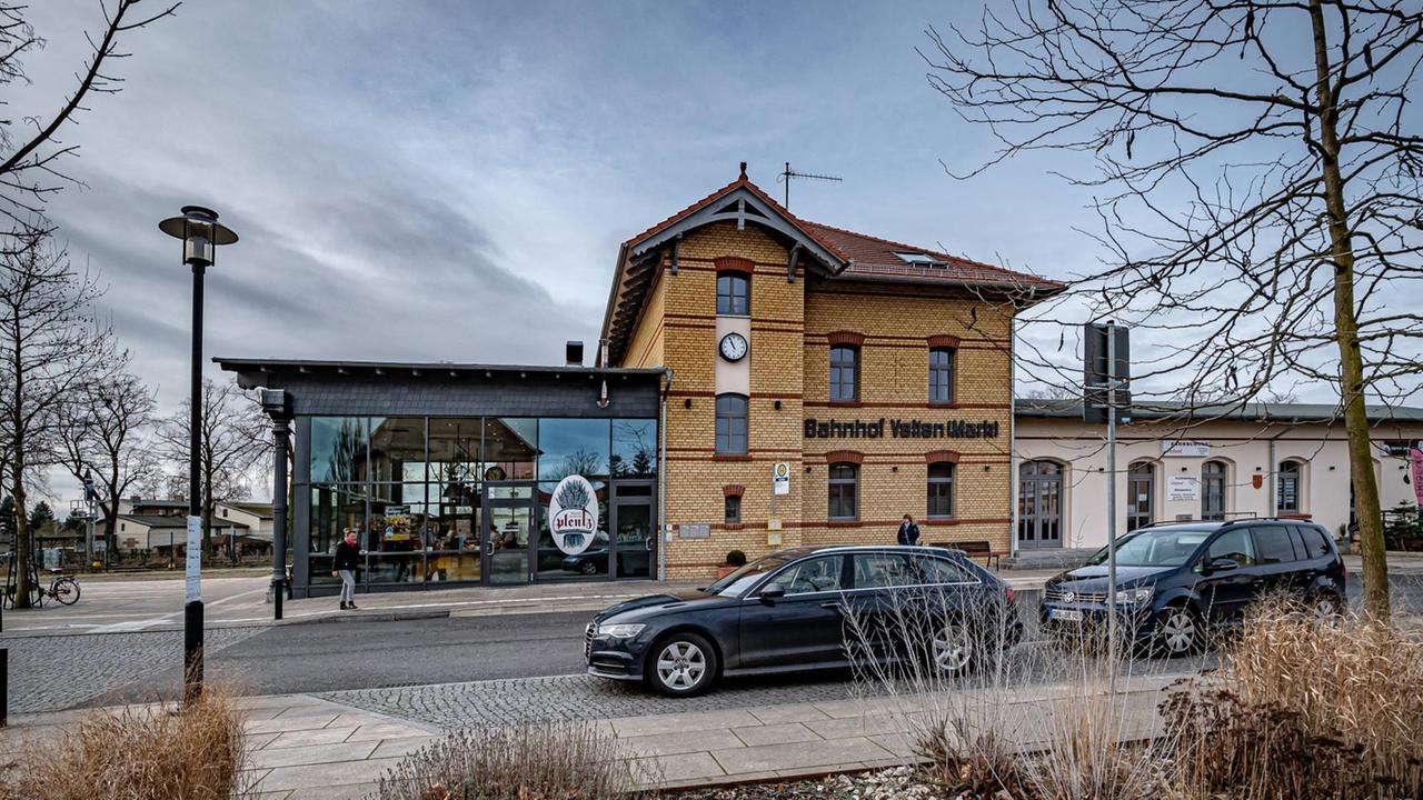 Velten im Landkreis Oberhavel, Bundesland Brandenburg: Vor dem Bahnhof verläuft einen Straße, im Vordergrund parkt ein schwarzes Auto. Velten im Landkreis Oberhavel, Bundesland Brandenburg: Vor dem Bahnhof verläuft einen Straße, im Vordergrund parkt ein schwarzes Auto.